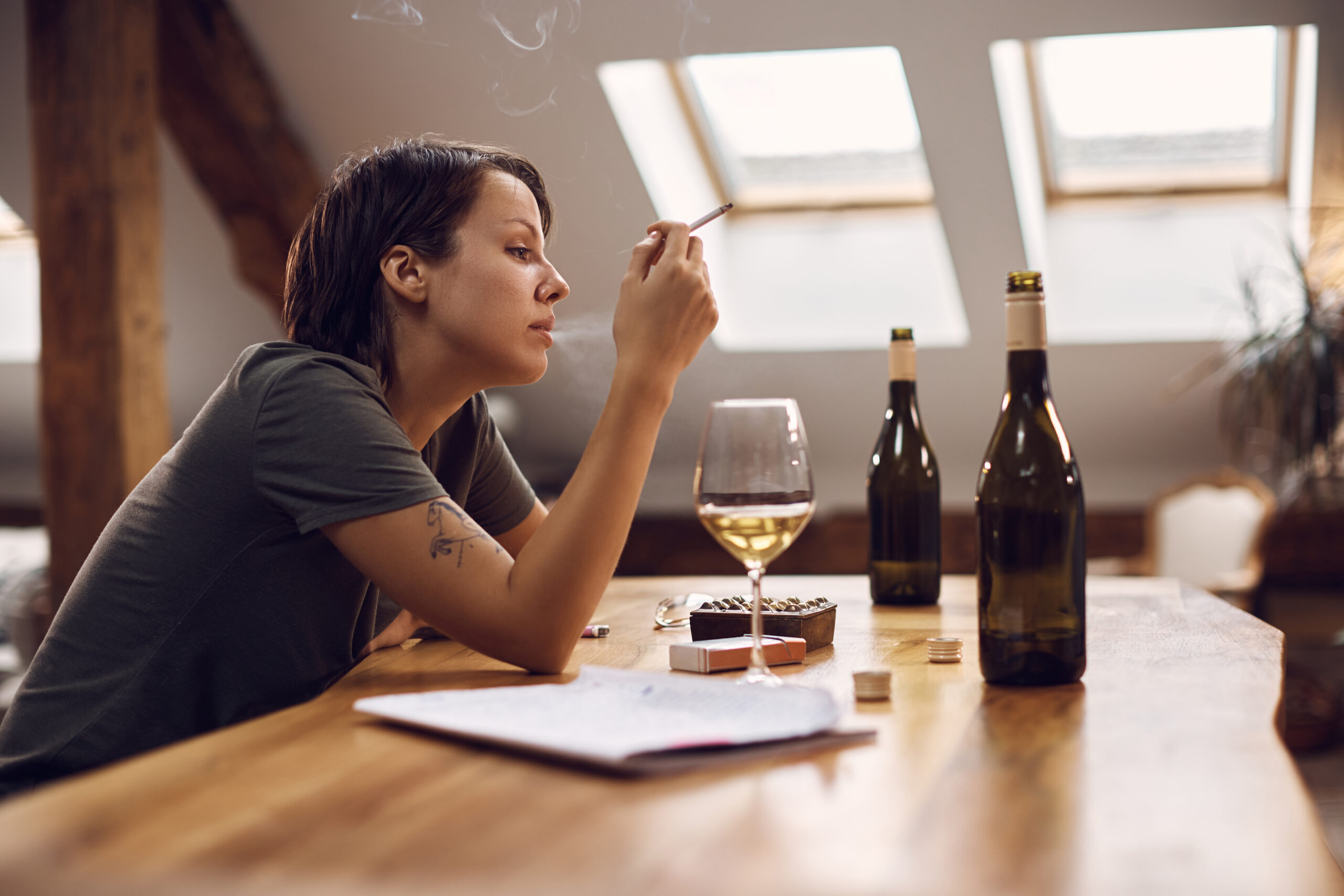 Woman smoking cigarette and drinking alcohol, illustrating alcohol abuse and mental health impact.