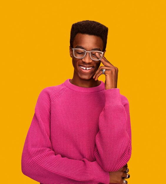 Smiling person wearing glasses and a pink sweater, lifestyle portrait by Wesley Moore.