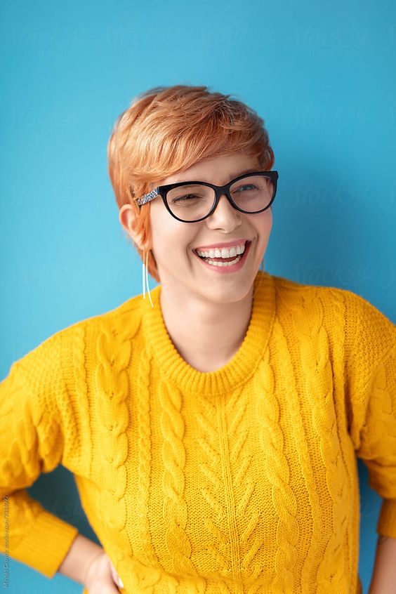 Gwen Cooke, author, smiling and wearing glasses and a yellow sweater.
