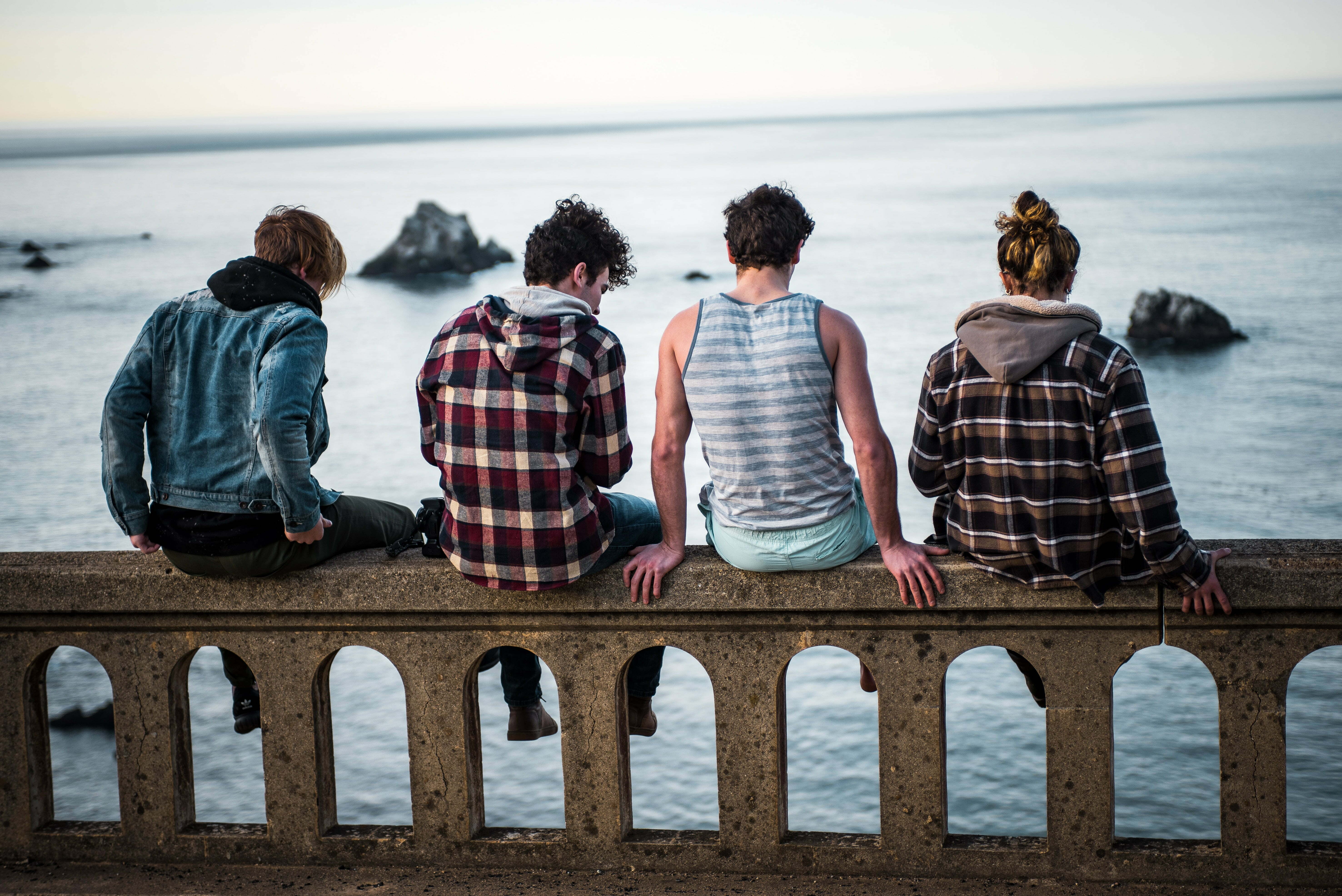 a group of people sitting on a bench looking at the water