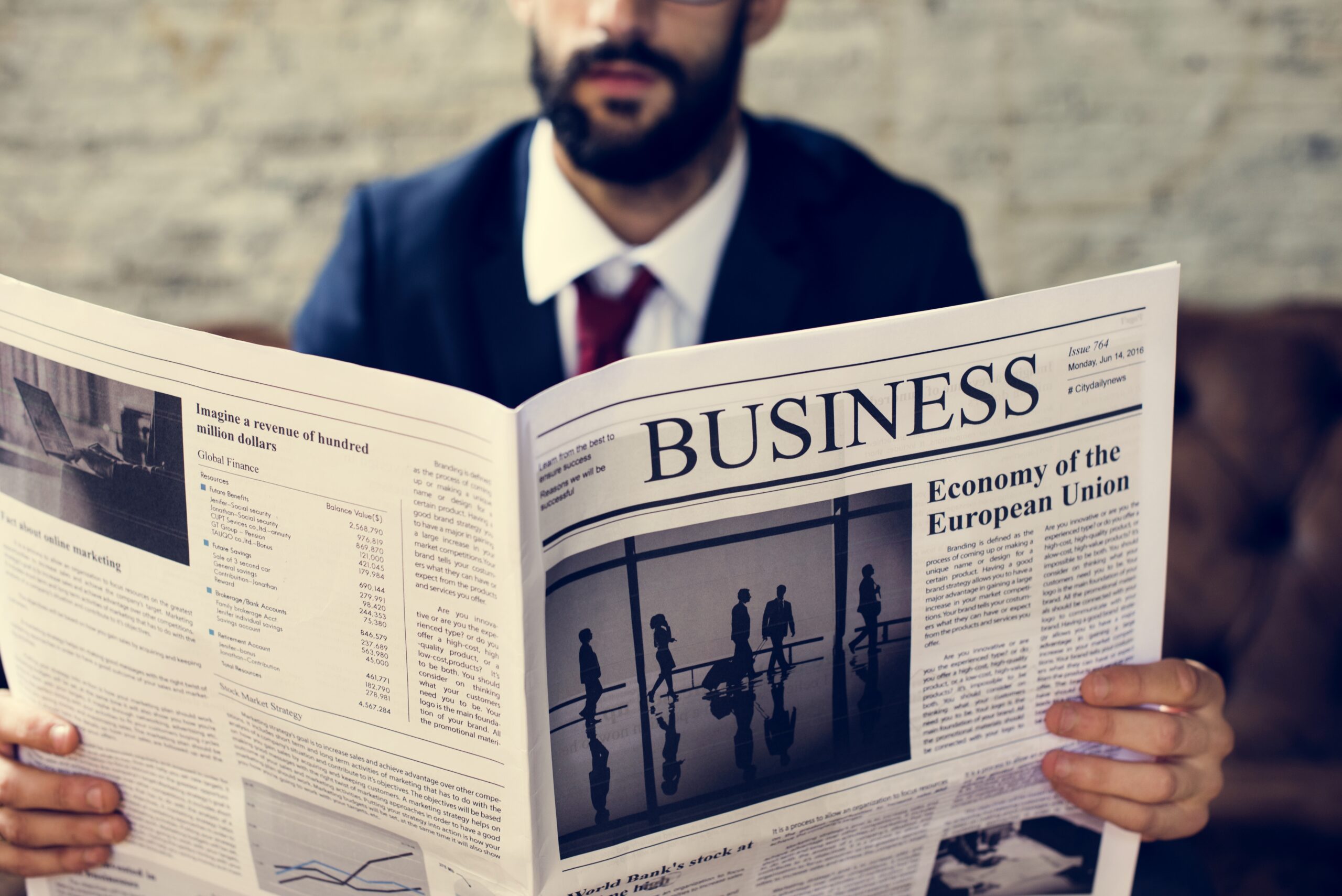 Businessman reading newspaper about current events and global news.