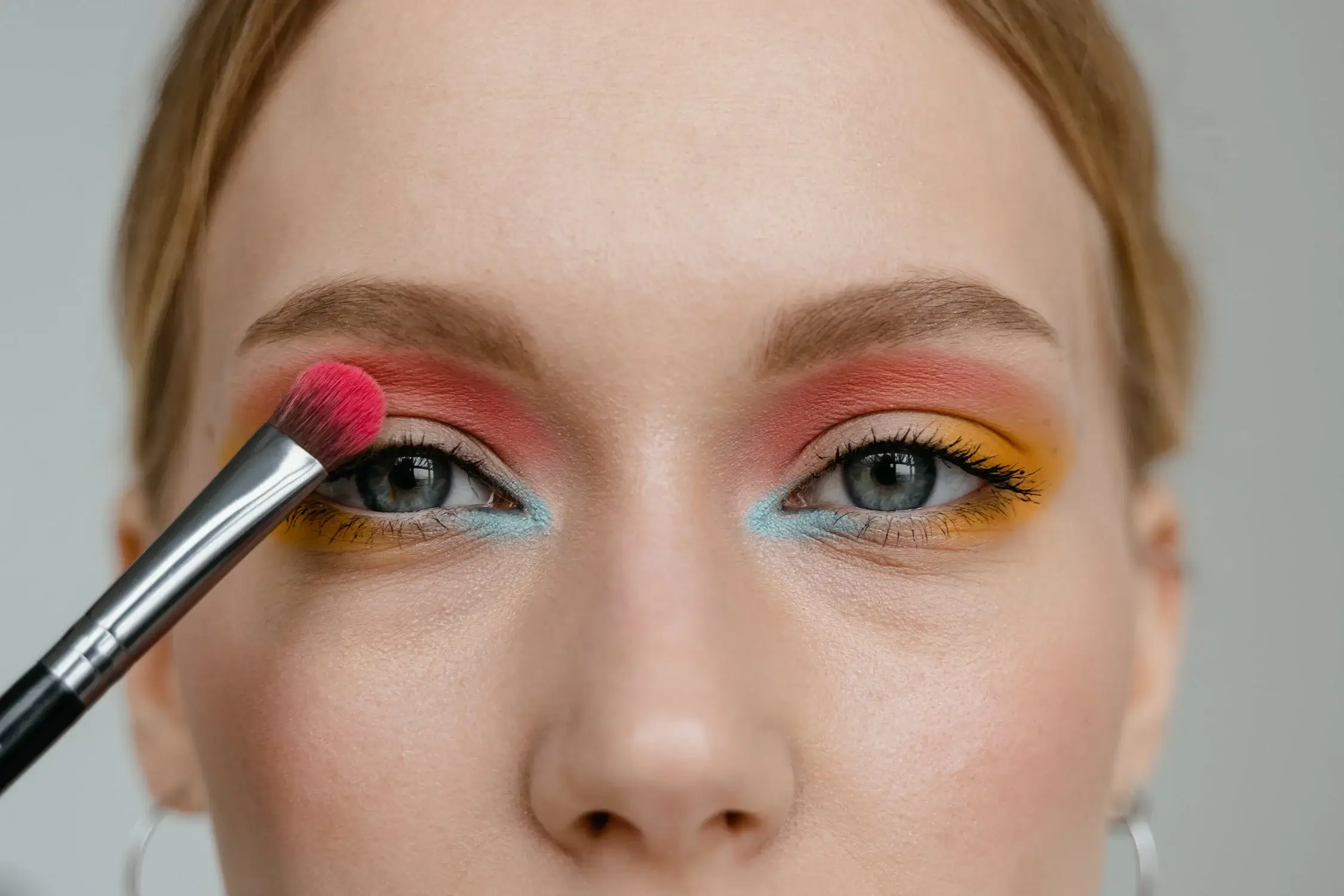 Close-up of eye makeup application and colorful eyeshadow palette.
