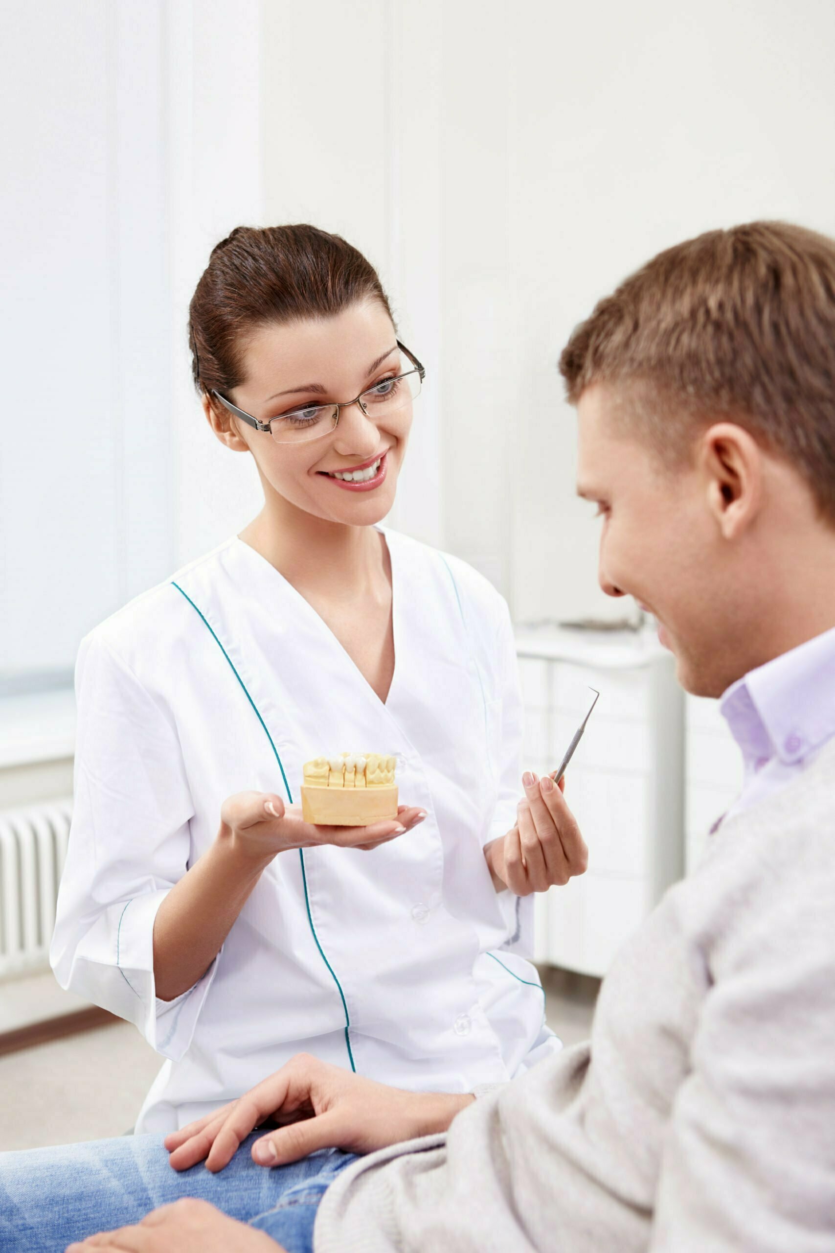 Healthcare professional discussing dental model with patient, exploring career paths in healthcare.