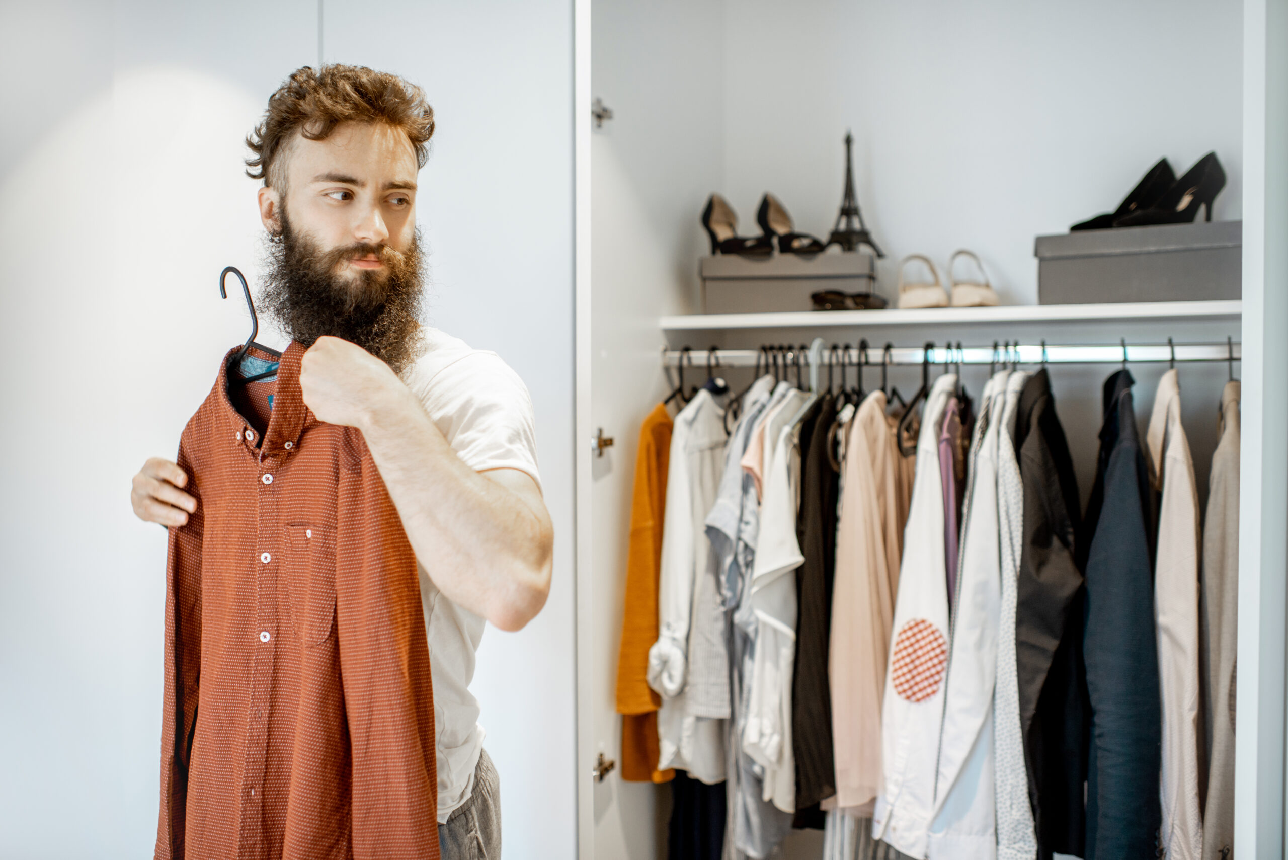 Man examining shirt in wardrobe, personal style fashion trends