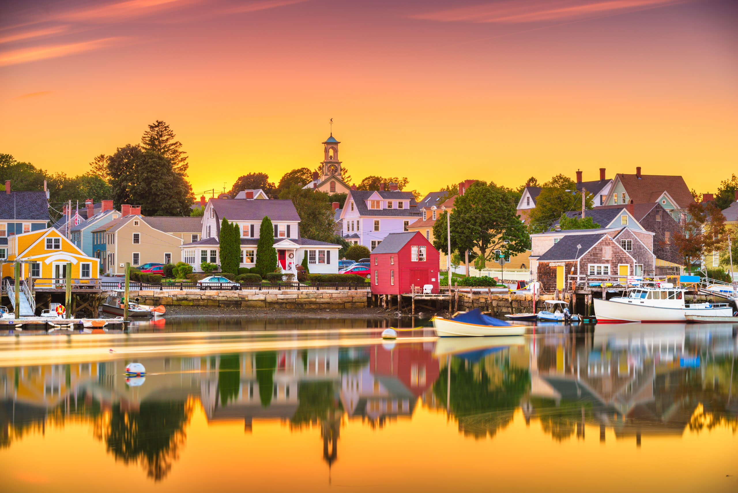 Colorful townscape and waterfront reflecting sunset, showcasing unique hospitality and local charm.